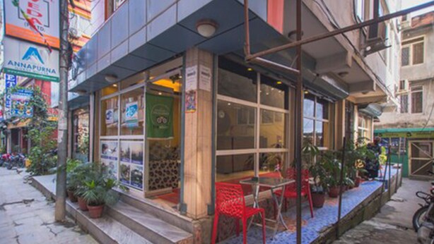 Een restaurant met terras, plantenbakken en een bord waarop 'ANNAPURNA' staat.