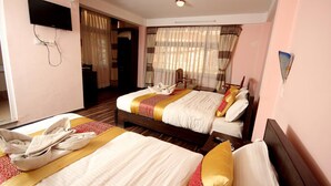 Een hotelkamer met twee bedden, een televisie en een raam met gordijnen.