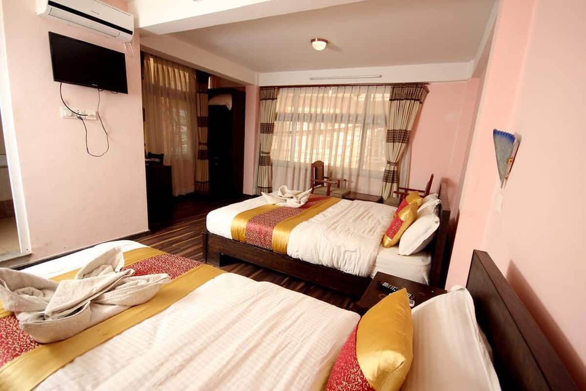 A hotel room with two beds, a TV, and a window with curtains.