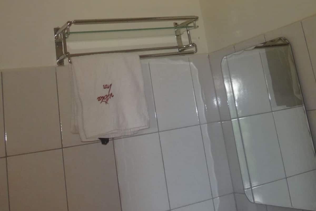 A bathroom with a glass shower enclosure, a towel rack, and a mirror.
