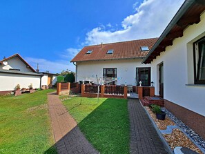 A residential house with a tiled roof, a brick pathway, and a well-maintained lawn.