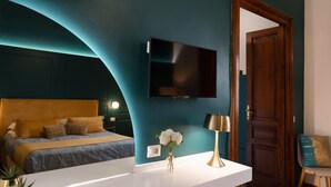 A modern bedroom with a bed, a TV, a desk, and a chair. - La Lepre Felice (Naples)