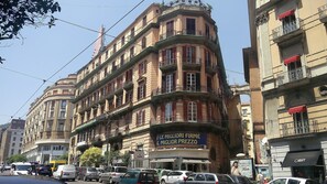 A multi-story building with balconies, a sign for a clothing store, and parked cars on the street. - La Lepre Felice (Naples)