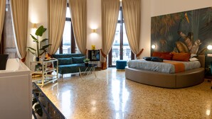 A modern living room with a round sofa, a green armchair, a small table, and a large painting on the wall. - La Lepre Felice (Naples)