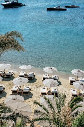 Na praia, espreguiçadeiras, guarda-sóis, toalhas de praia 