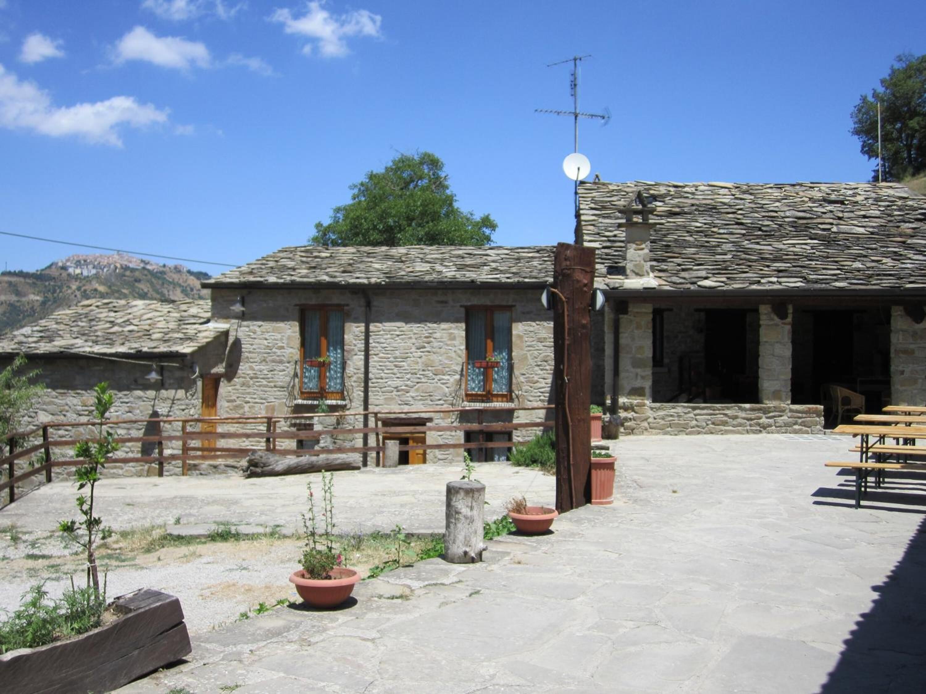 Un edificio in pietra con tetto in tegole, un'antenna parabolica e una recinzione in legno.