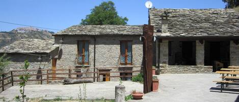 A stone building with a tiled roof, a satellite dish, and a wooden fence.