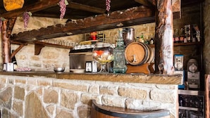 A rustic bar area with stone walls, wooden beams, and various bar tools and bottles. - Agriturismo Grotta Dell'Eremita (Castelmezzano)