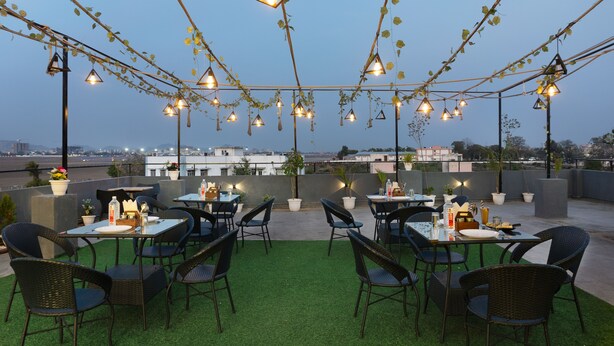 An outdoor patio with tables and chairs, string lights, and potted plants. - Treebo Dream Palace Near Jaipur International Airport (Jaipur)