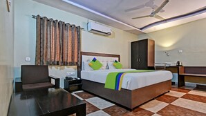 A hotel room with a bed, a desk, a chair, an air conditioning unit, a wardrobe, and a ceiling fan. - Treebo Dream Palace Near Jaipur International Airport (Jaipur)