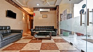 A hotel lobby with a checkered floor, leather sofas, a glass partition, and a ceiling fan. - Treebo Dream Palace Near Jaipur International Airport (Jaipur)