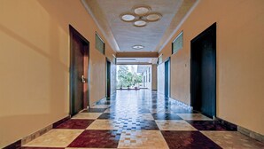 A long hallway with checkered flooring, a ceiling with a circular design, and doors on both sides. - Treebo Dream Palace Near Jaipur International Airport (Jaipur)