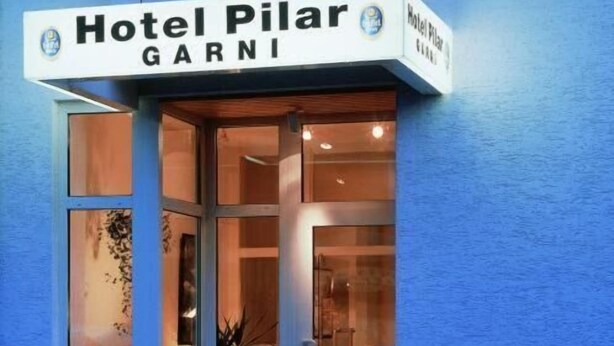 The entrance to Hotel Pilar Garni with a glass door and a potted plant outside. - Hotel Pilar Garni (Cologne)