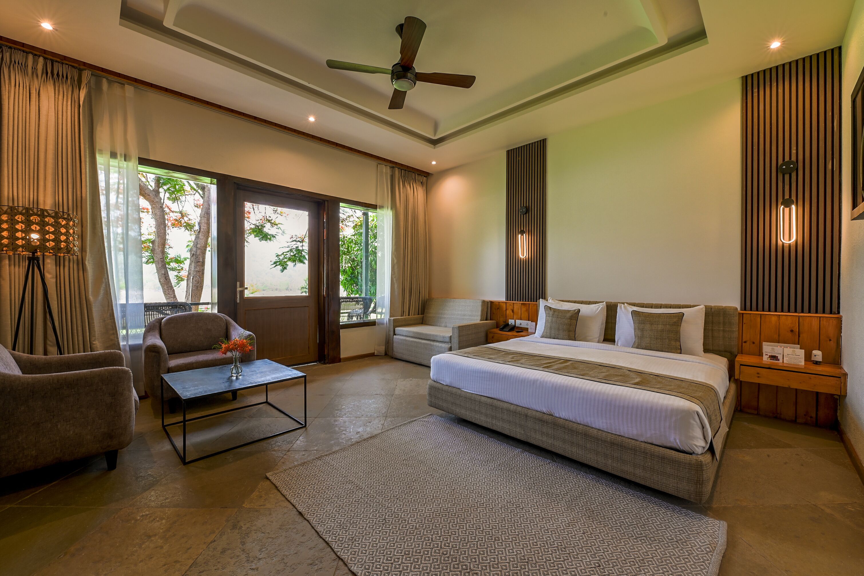 A bedroom with a large bed, a sofa, a coffee table, and a ceiling fan.
