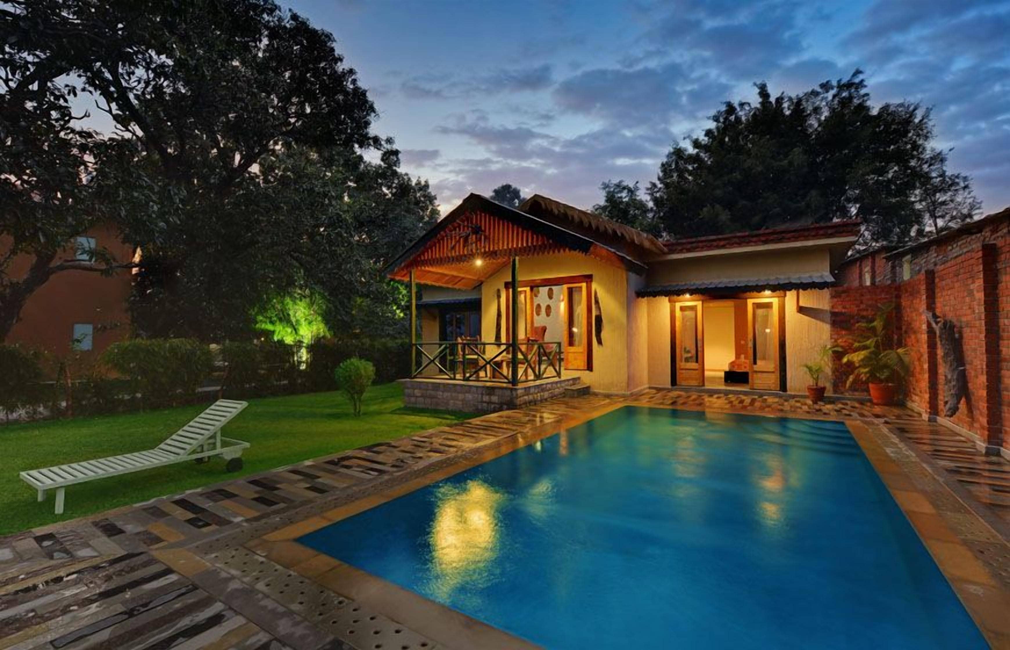 A swimming pool with a wooden deck, a covered outdoor seating area, and a brick wall.