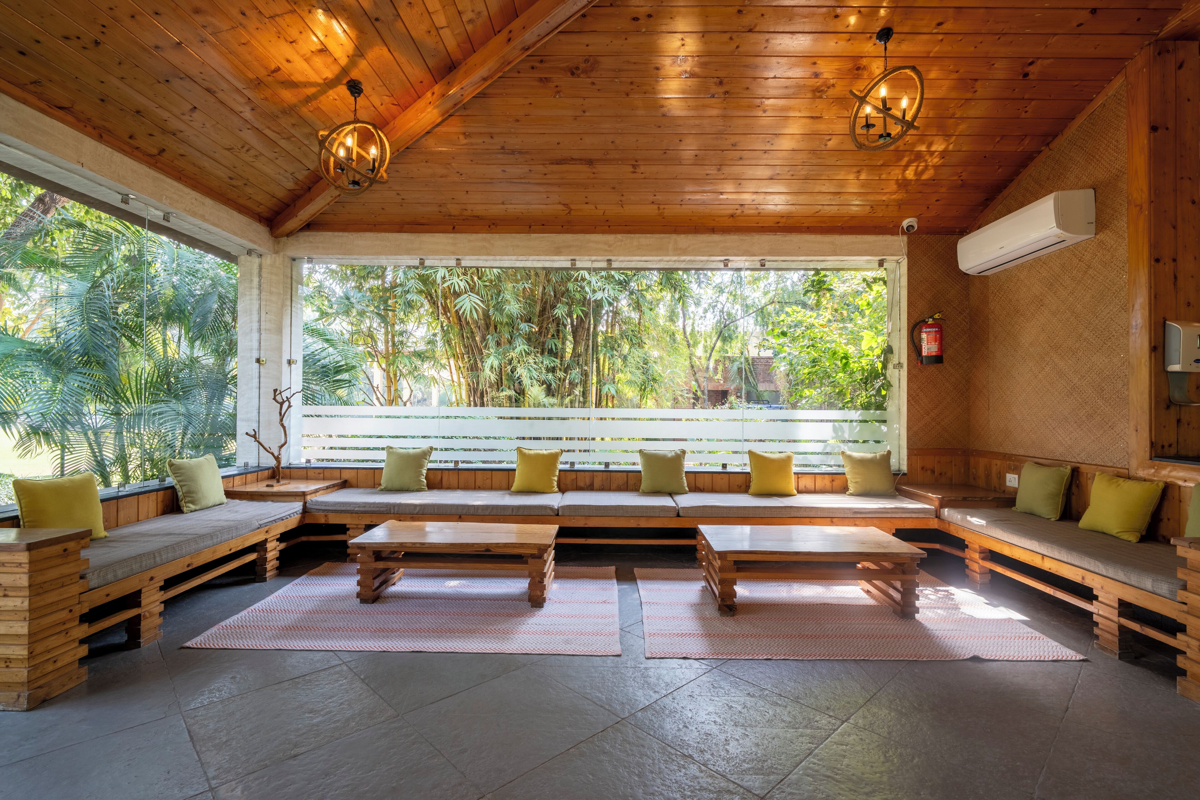 A spacious room with wooden furniture, large windows, and a view of greenery.