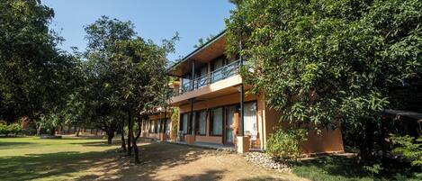 A two-story building with a balcony, surrounded by trees and a well-maintained lawn.