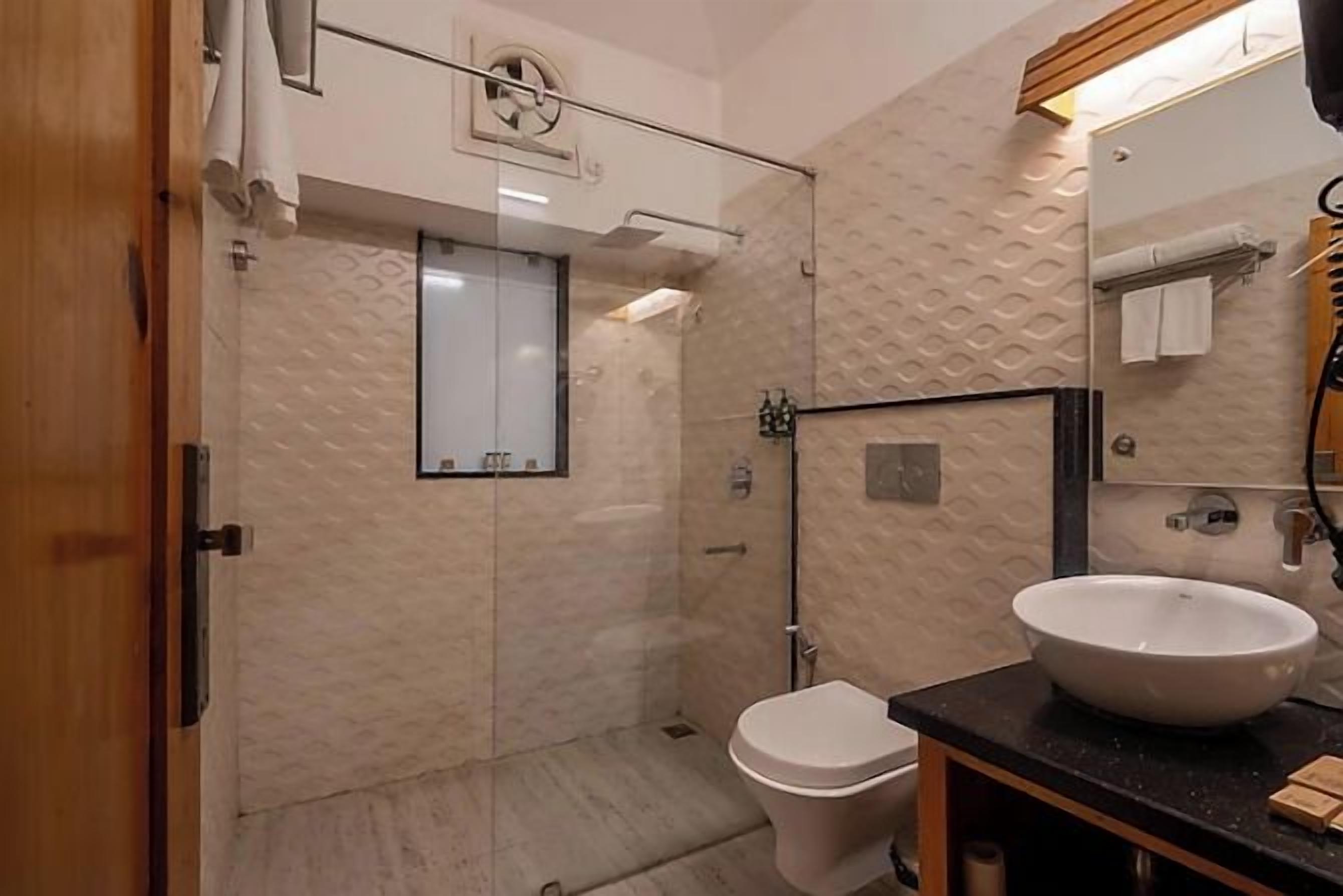 A bathroom with a glass-enclosed shower, a white sink, and a mirror.