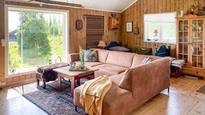 En hyggelig stue med et stort vindue, en sofa, et sofabord og et skab med glaslåger.