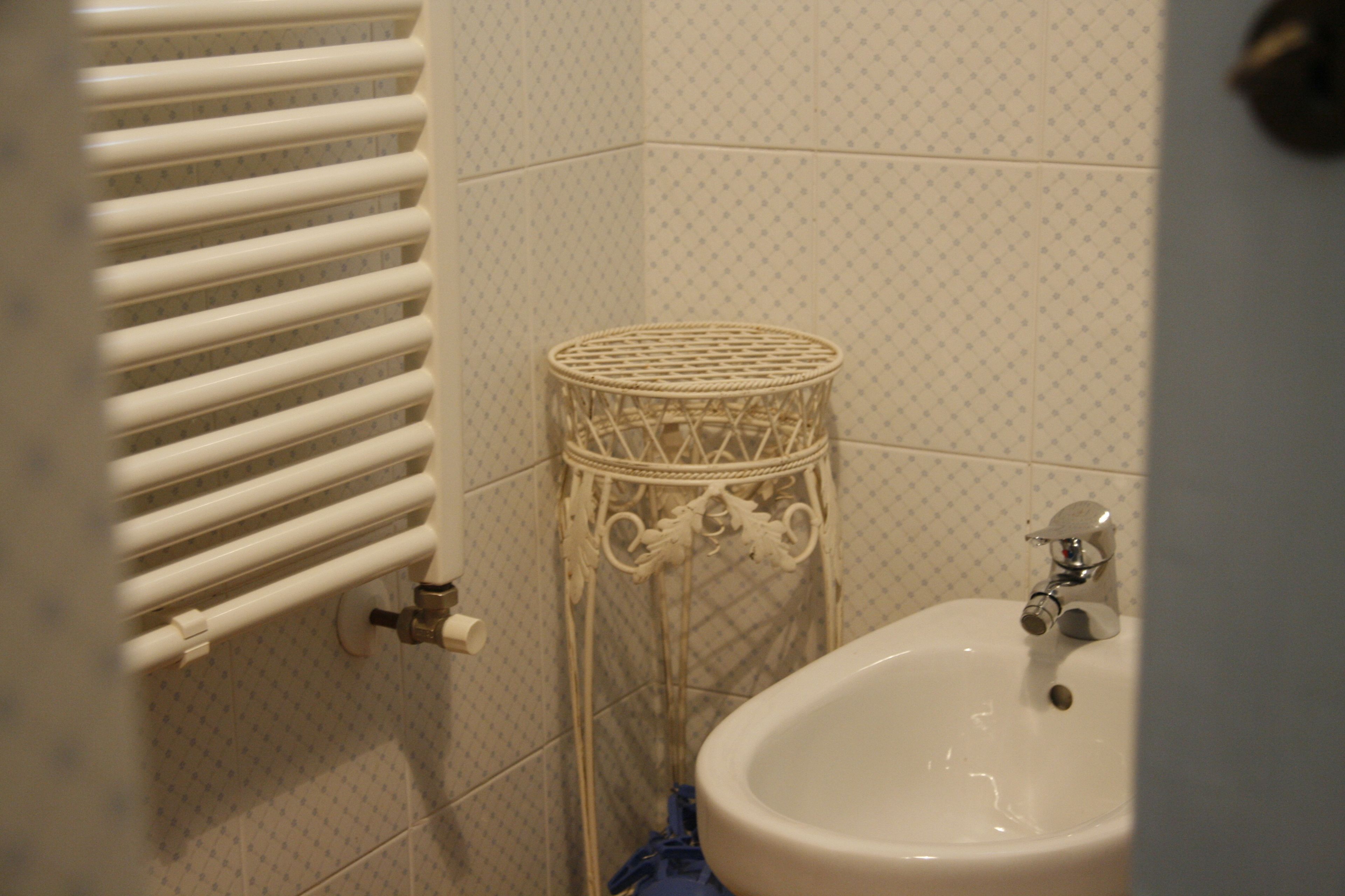 A bathroom with a white radiator, a wicker basket, and a sink.