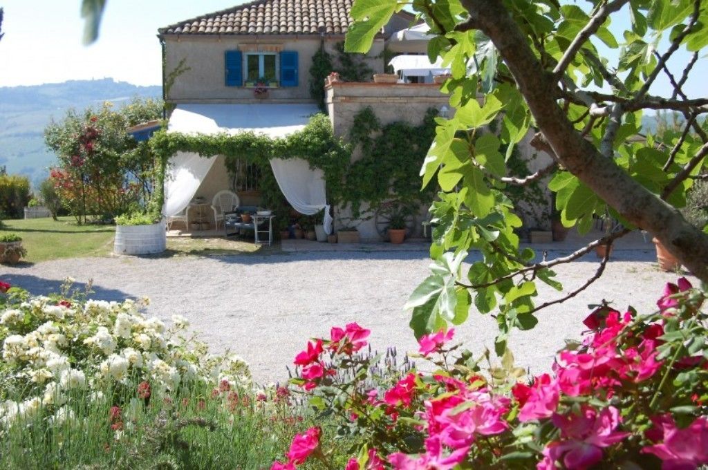 Une maison avec une allée en gravier, un espace extérieur aménagé et couvert, et un jardin fleuri.