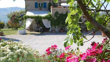 Une maison avec une allée en gravier, un espace extérieur aménagé et couvert, et un jardin fleuri.