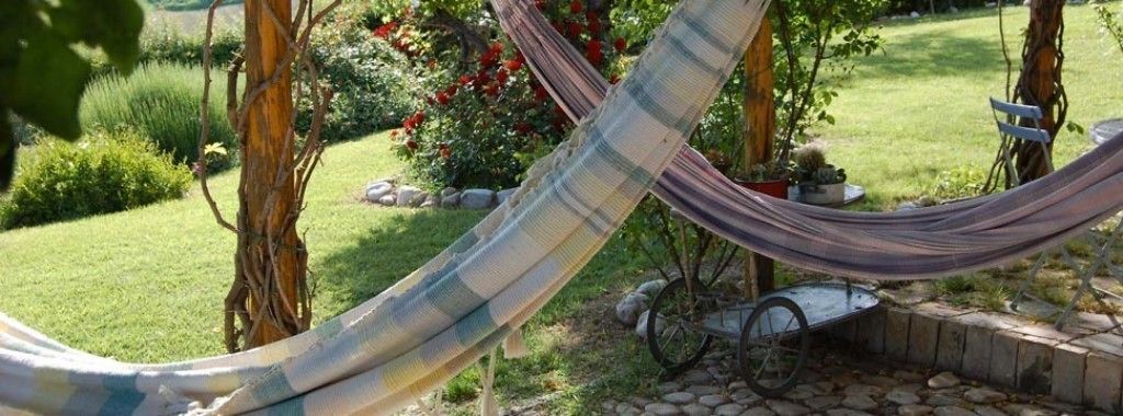 Una hamaca en un jardín con un sendero de piedra y una carretilla.