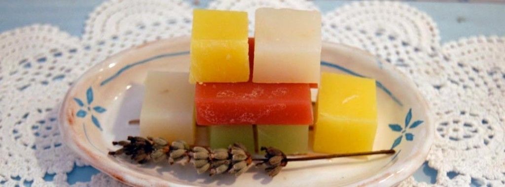 Ein Teller mit unterschiedlich farbigen Lebensmittelflecken, möglicherweise Käse, auf einem weißen Teller mit blumigem Dekor, platziert auf einer Spitzendecke.