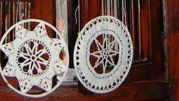 Deux poignées de porte métalliques blanches, de forme circulaire et dotées de motifs complexes, sont fixées à une porte en bois ornée de panneaux verticaux.