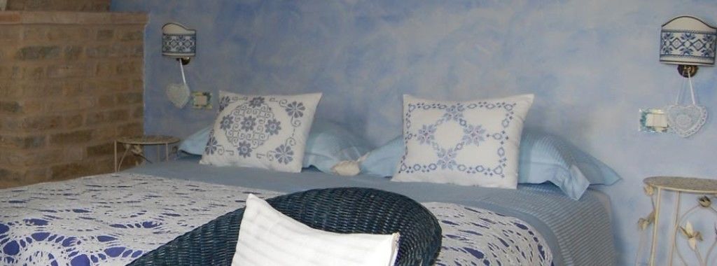 A bedroom with a bed, two wall-mounted lamps, and a small table.