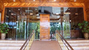 Un interior de madera con una escalera central, puertas de cristal y plantas en macetas.