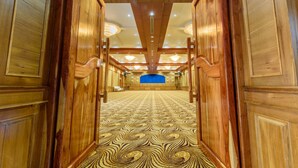 Un pasillo con paneles de madera y una alfombra estampada que conduce a una zona de escenario.