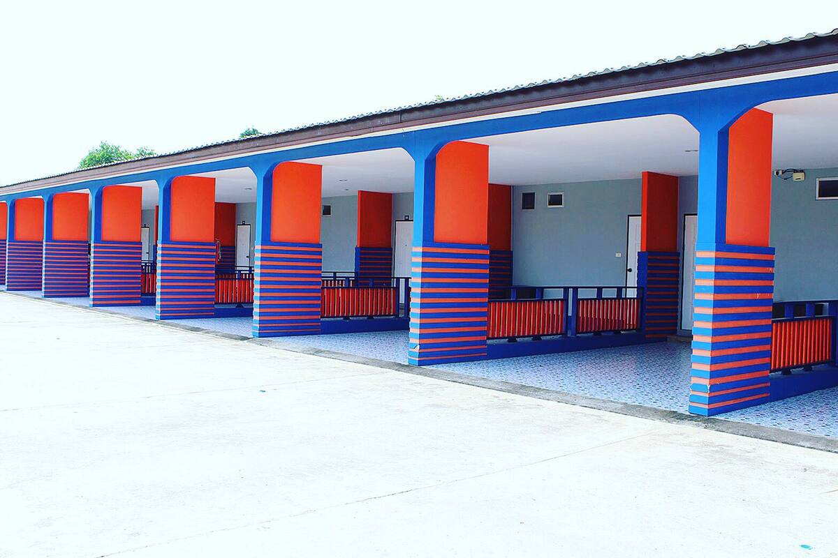 A row of blue and red striped columns supporting a covered walkway with benches.