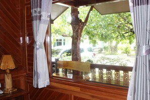 A wooden paneled room with a window overlooking a tree and parked cars. - Sky View Resort Buriram (Buriram)