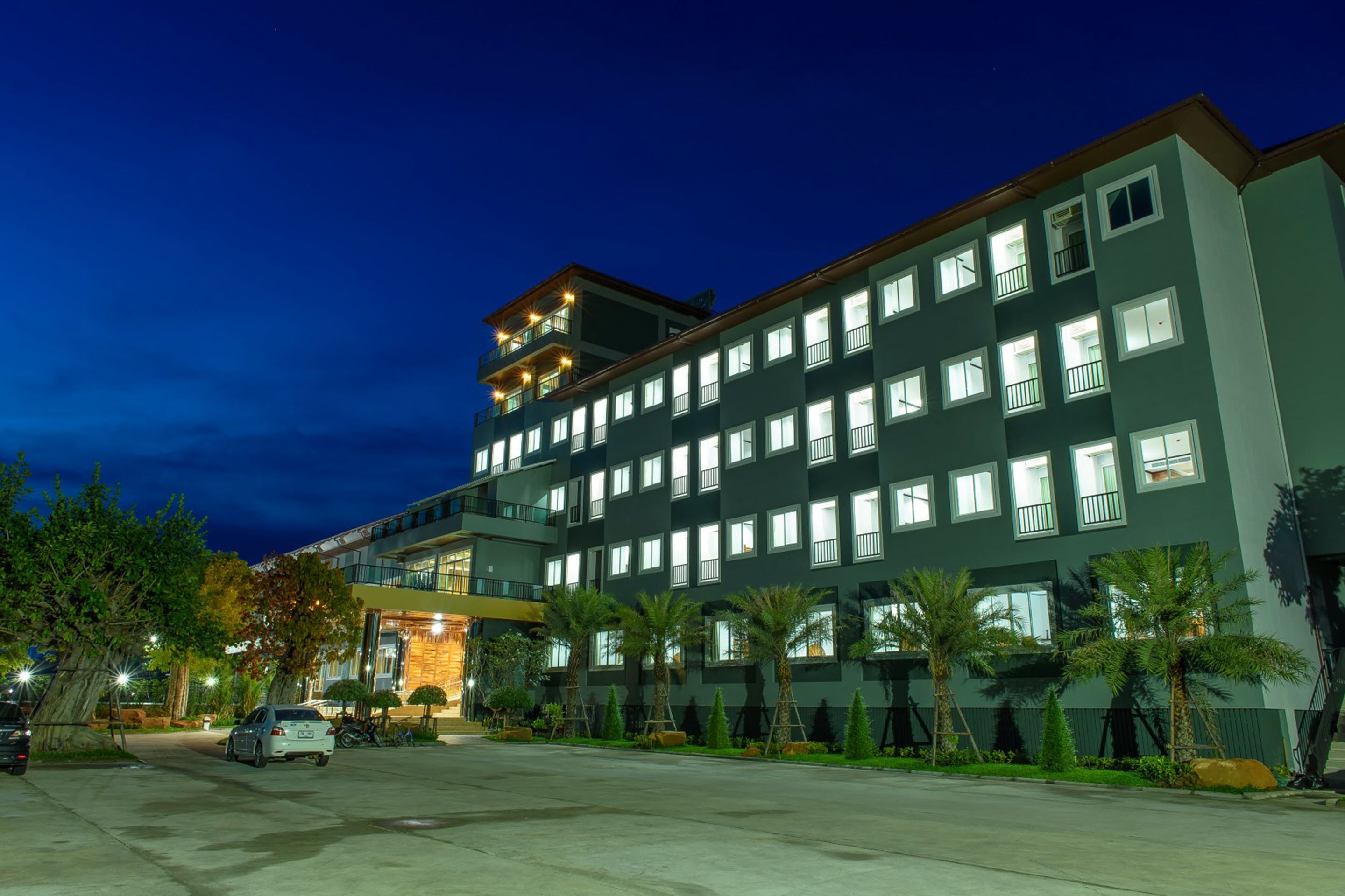 A multi-story hotel with a modern design, featuring a parking area and well-maintained landscaping.