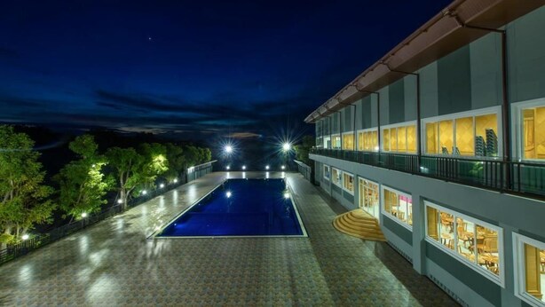 Un hotel con piscina, iluminación exterior y vistas al cielo nocturno.