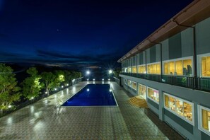Un hotel con piscina, iluminación exterior y vistas al cielo nocturno.