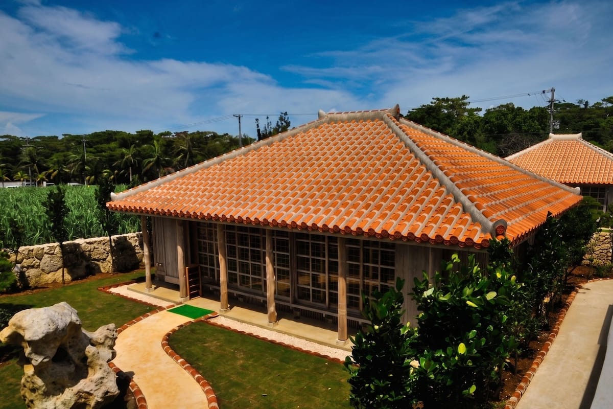 A traditional building with a tiled roof, large windows, and a stone pathway leading to it.