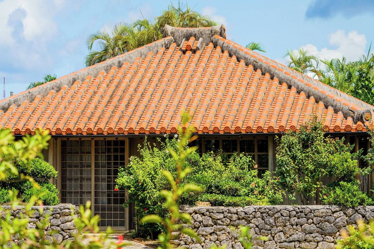 A traditional building with a tiled roof, stone wall, and window with a grid pattern.