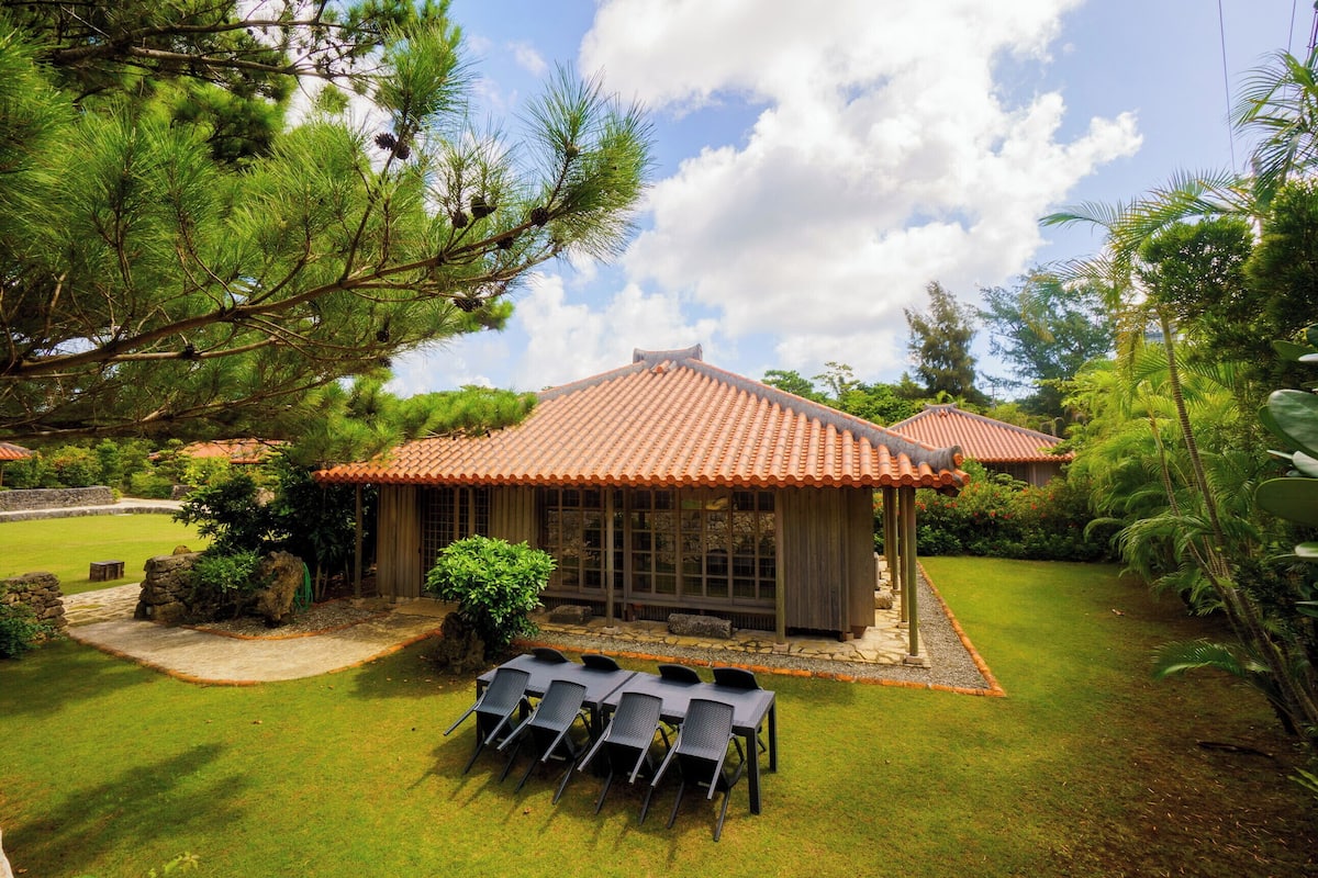 A traditional building with a tiled roof, surrounded by a well-maintained lawn and trees.