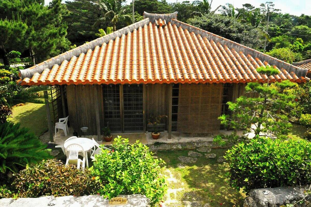 A traditional building with a tiled roof, a wooden door, and a small garden area with a table and chairs.