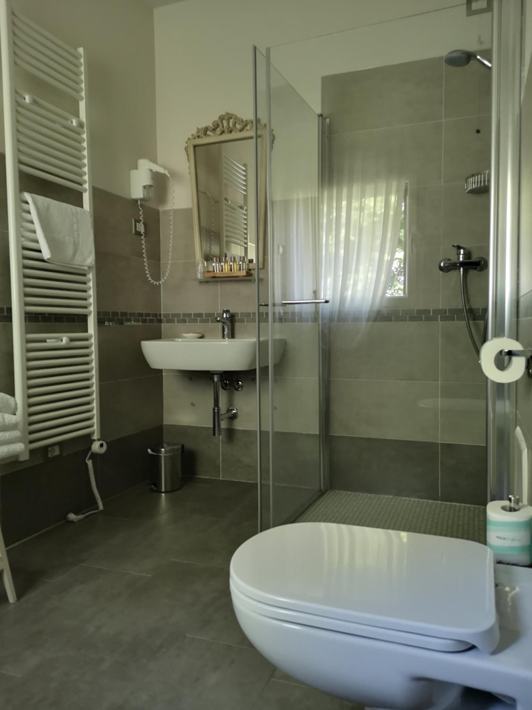 Ein modernes Badezimmer mit einer Duschkabine aus Glas, einem weißen Waschbecken und einer Toilette.