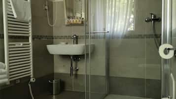 Ein modernes Badezimmer mit einer Duschkabine aus Glas, einem weißen Waschbecken und einer Toilette.