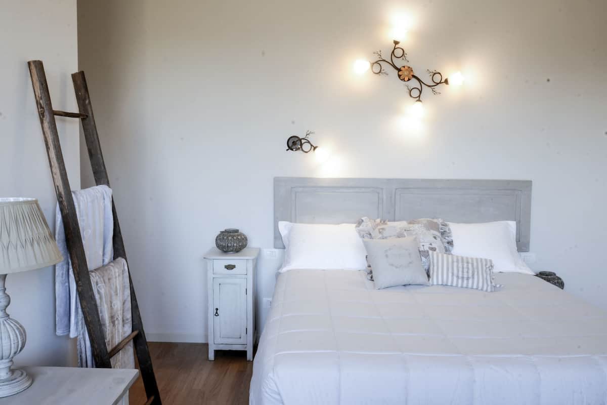 A bedroom with a bed, bedside table, lamp, and a decorative wall light.