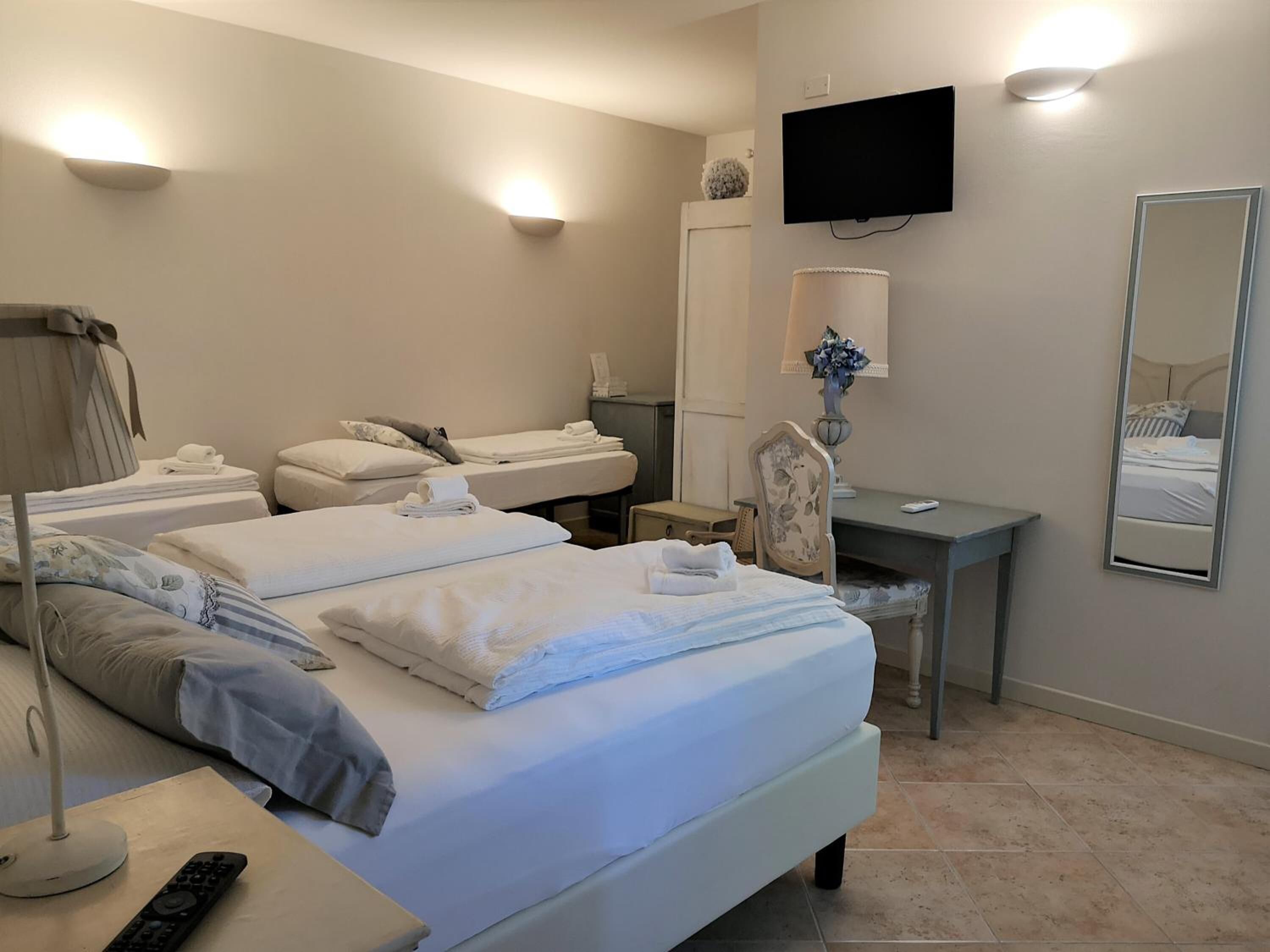 A hotel room with two beds, a desk, a chair, a TV, and a mirror.