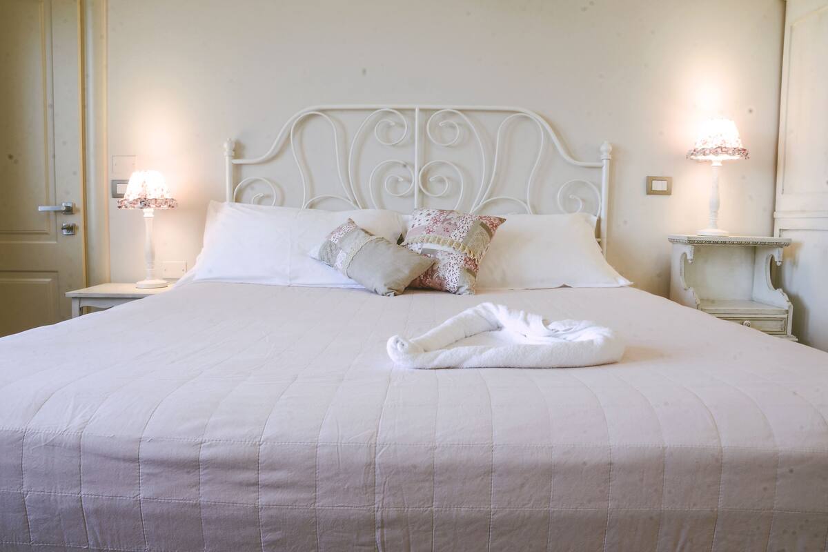 A neatly made bed with a quilted bedspread, two pillows, and a folded towel on the bed.