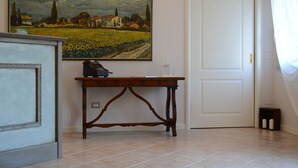 Une pièce avec une table en bois, un tableau, une porte blanche et un sol carrelé.