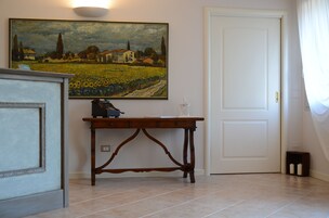 Una stanza con un tavolo di legno, un quadro, una porta bianca e un pavimento piastrellato.