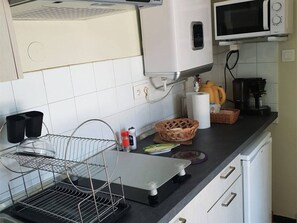 A kitchen with a microwave, coffee maker, and a metal rack.