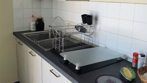 A kitchen with a double sink, a dish rack, a kettle, and a coffee maker. - Cozy Studio with Balcony, Steps from the Beach - Sleeps 4, A/C, Parking (Argelès-sur-Mer)